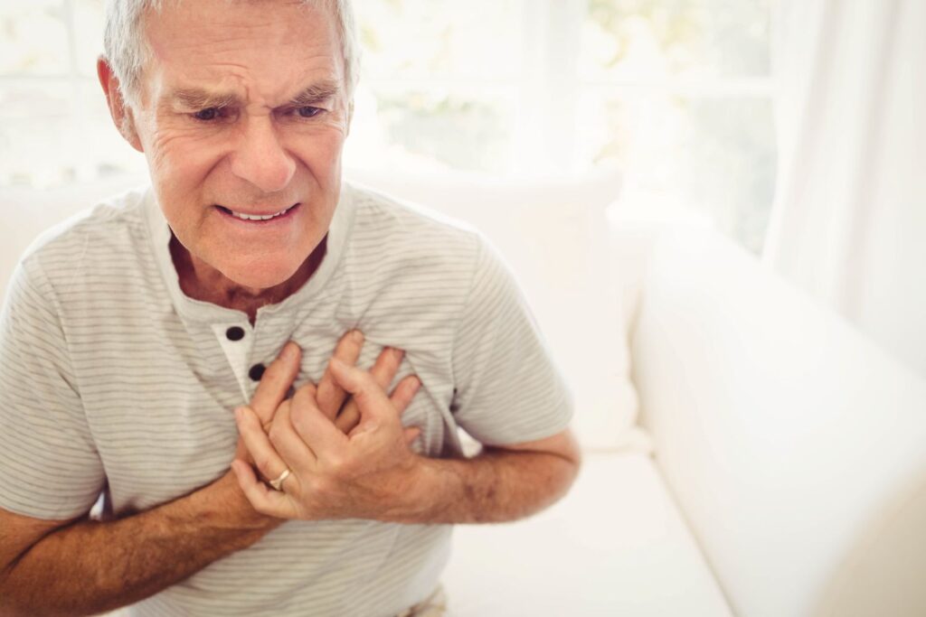 Homem segurando as mãos no peito para demonstrar fatores de risco AVC infarto.