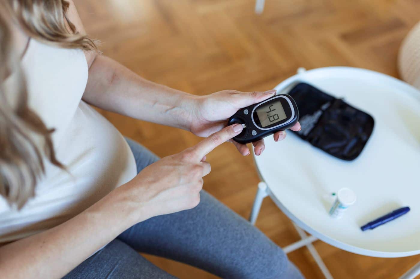 Mulher usando medidor digital de glicose, representando o controle doméstico de hipertensão e diabetes com tecnologia acessível.