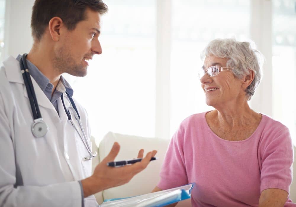 Médico explicando metas de colesterol para paciente idosa, representando acompanhamento cardiovascular especializado e orientações sobre prevenção.